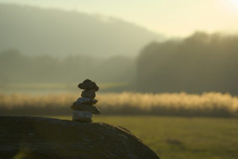 Stacked stones on a rock at sunrise