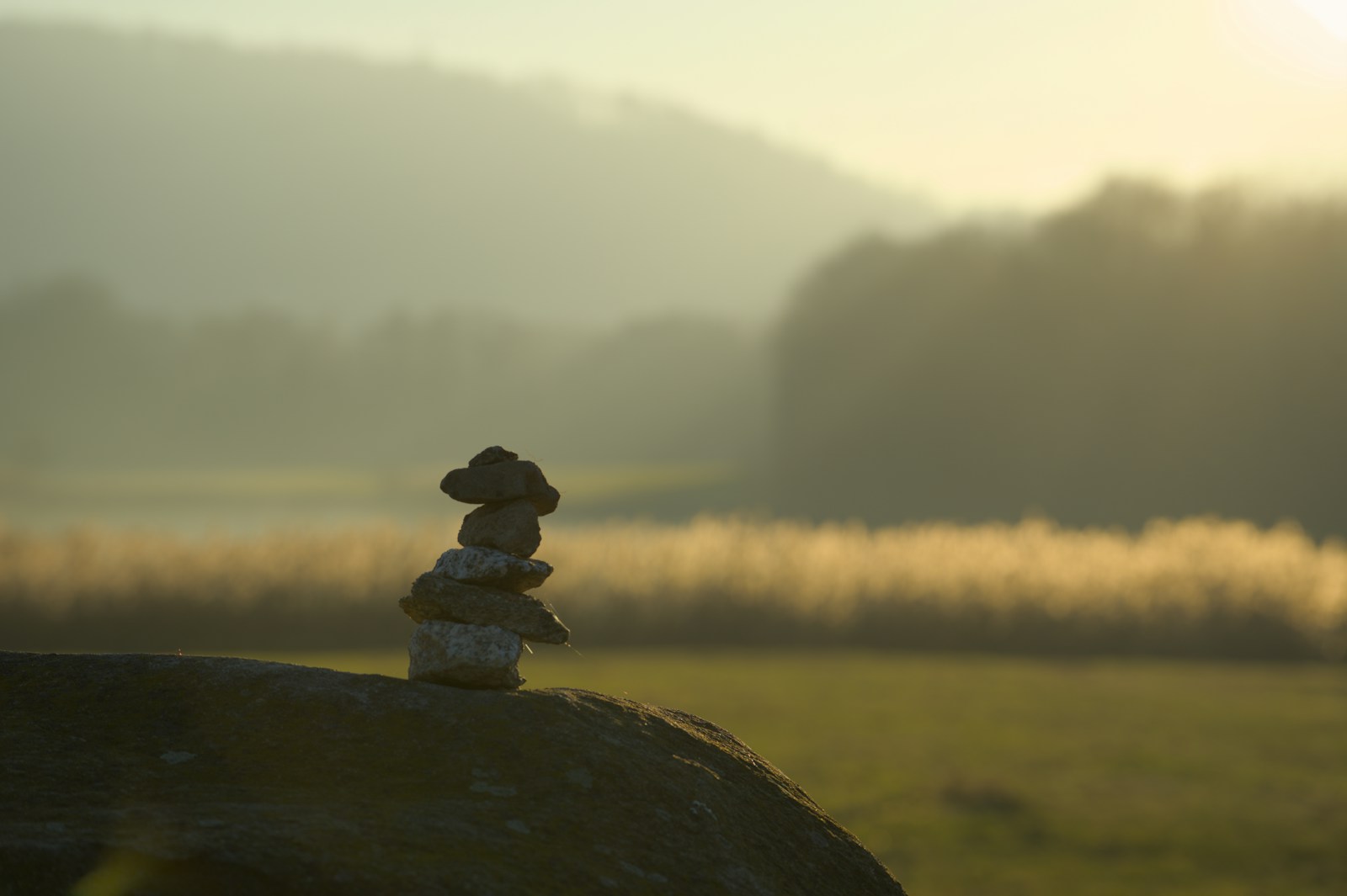 Stacked stones on a rock at sunrise