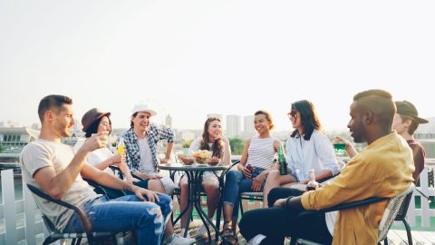 Friends enjoying drinks and snacks on a rooftop.