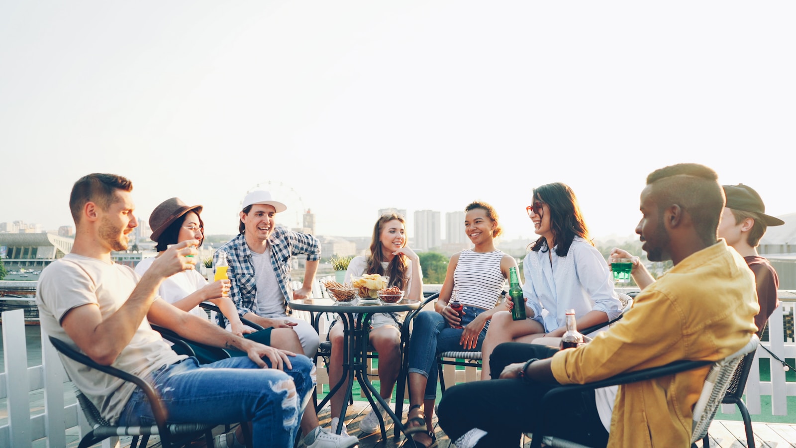 Friends enjoying drinks and snacks on a rooftop.